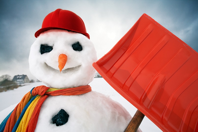 Snowman in a baseball hat holding a shovel