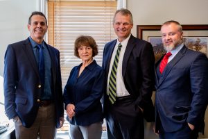 4 members of sales team standing together at a desk
